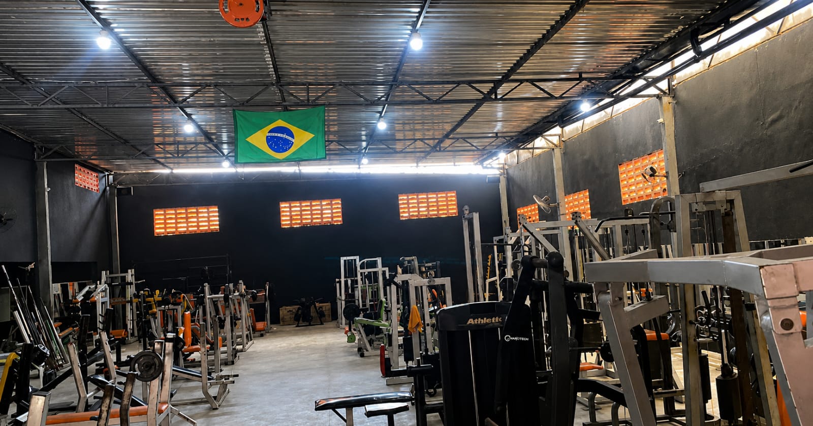 Área de musculação da Max Academia com racks de peso livre e máquinas de força